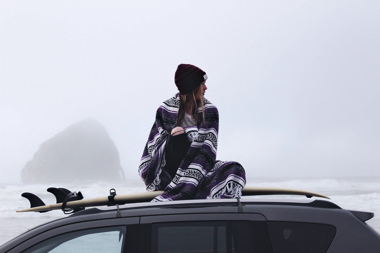 Frau sitzt auf dem Dach eines Autos.